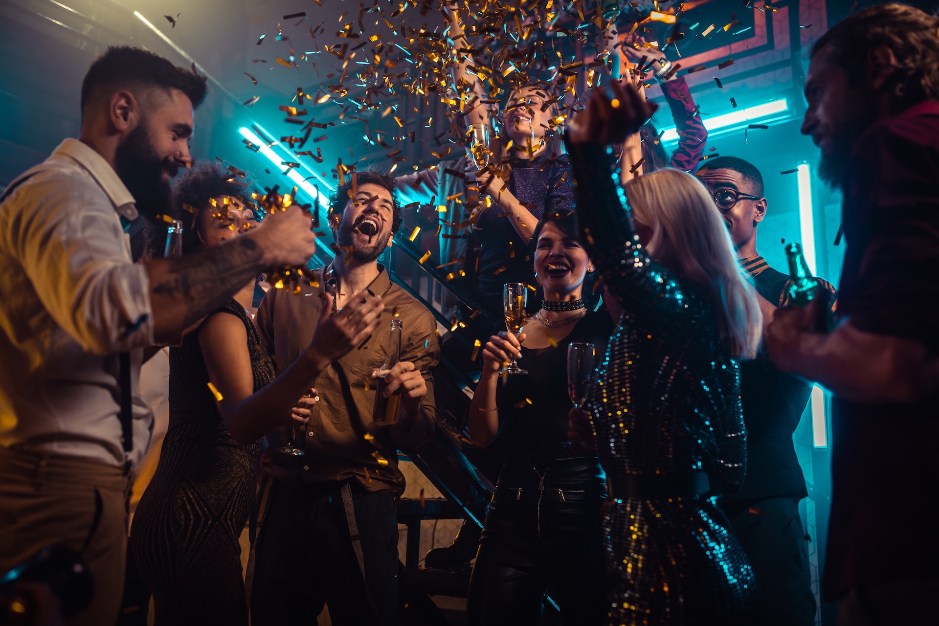Group of young friends drinking alcohol and dancing together in the nightclub Groupe de personnes célébrant avec confettis et champagne dans une soirée chic.