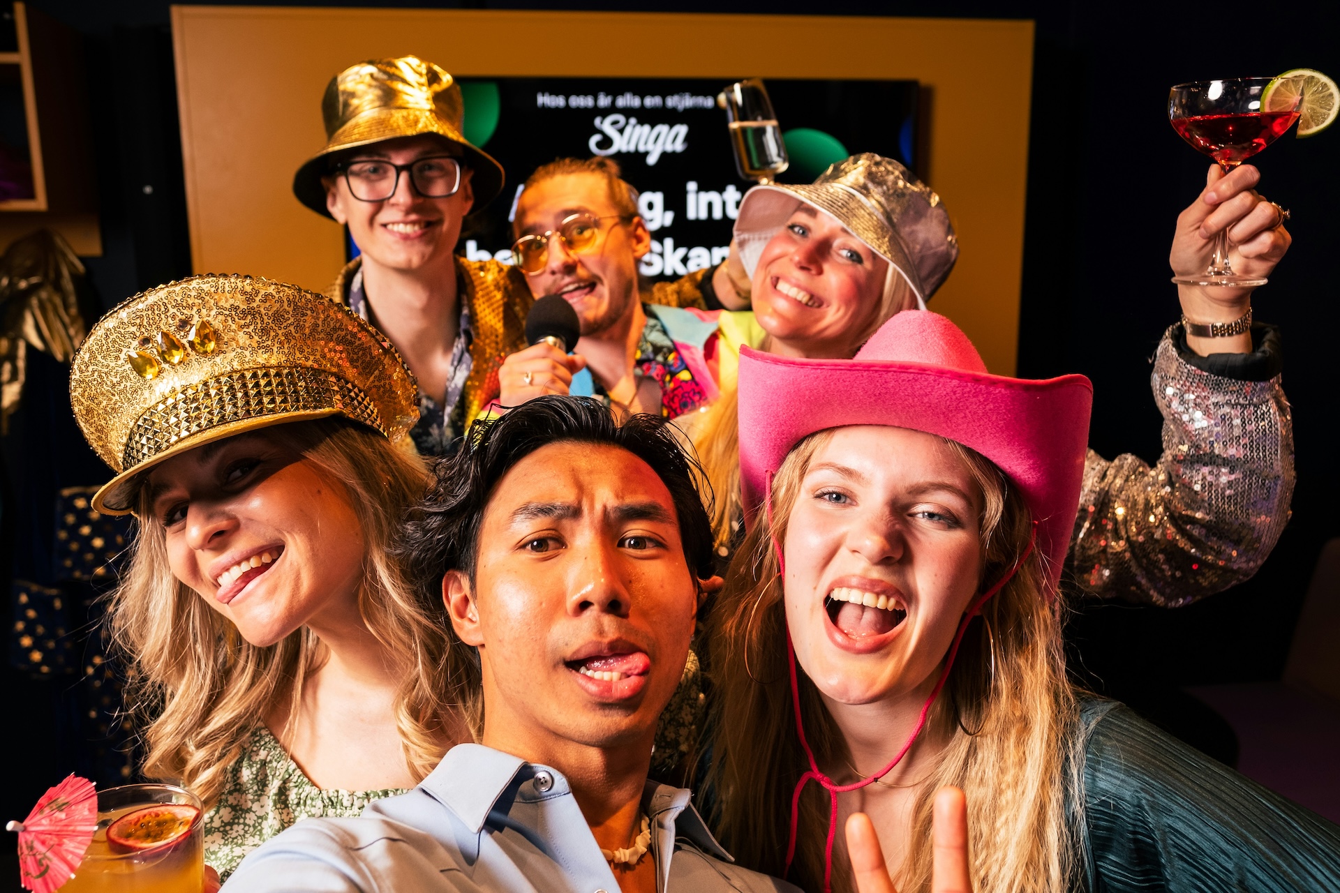 singa-karaoke-TV5YHK9Ce5U-unsplash Groupe d'amis en fête portant des chapeaux colorés et souriant.